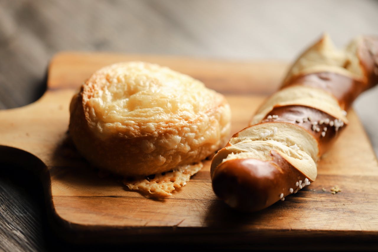 Gourmet cheese bread and pretzel on a wooden board. Perfect for bakery displays.