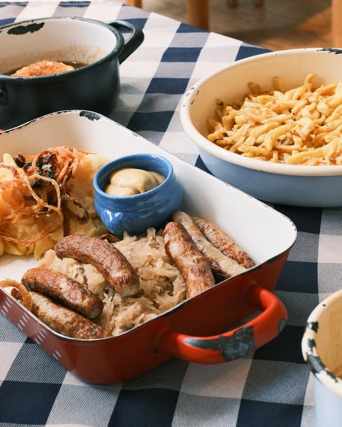 Authentic Bavarian cuisine featuring sausages, sauerkraut, and mustard on a checkered tablecloth.