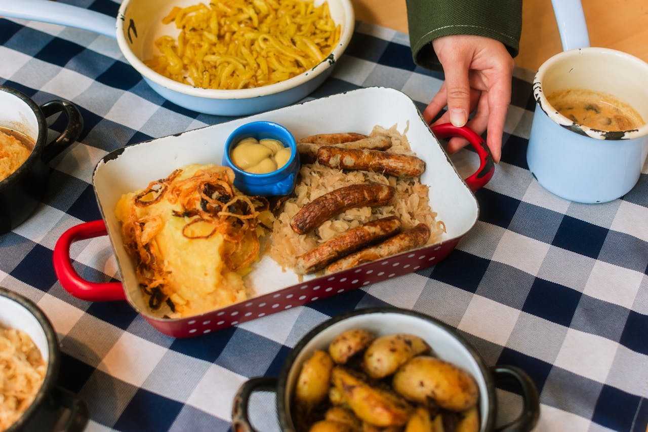 A homestyle Bavarian meal featuring sausages, potatoes, and sauerkraut on a checkered tablecloth.