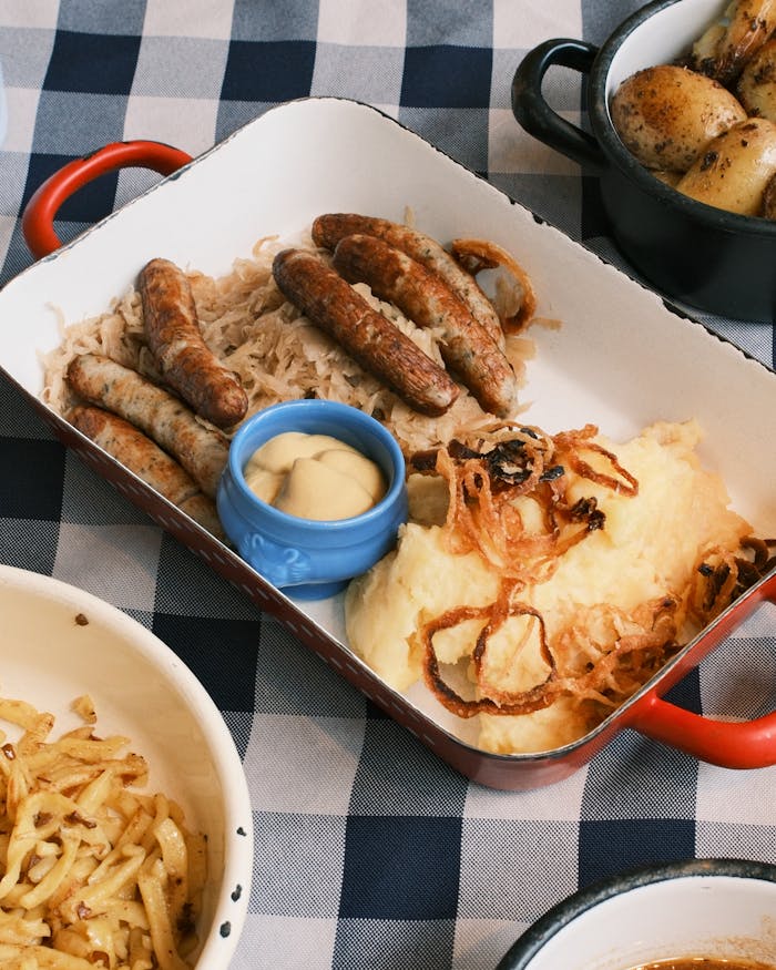 A delicious platter of German sausages, sauerkraut, and mashed potatoes, perfect for Oktoberfest.